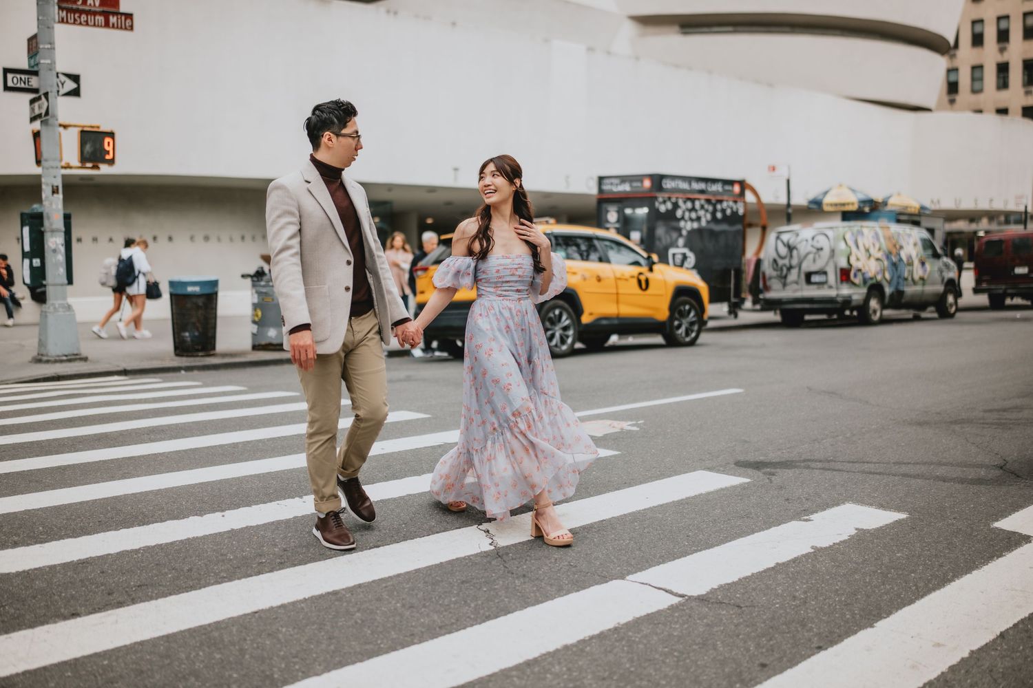 A couple crossing a city street crosswalk together in urban setting.