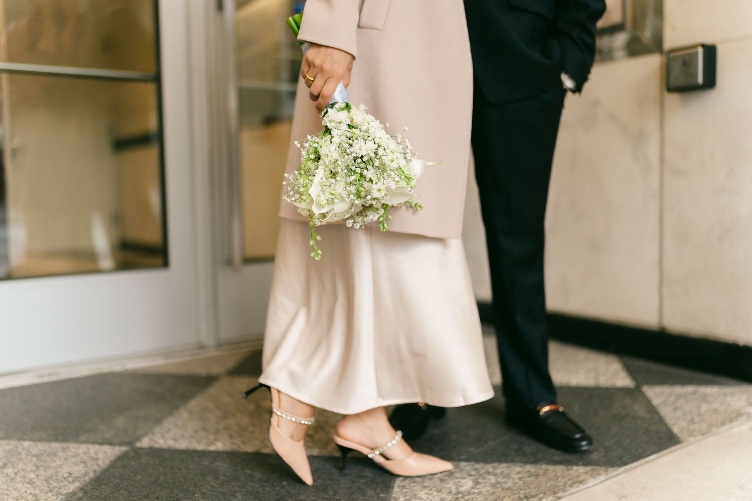 A couple walking together in formal attire with delicate floral bouquet details.