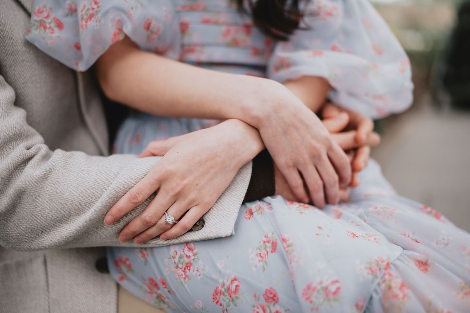 Close-up detail of hands and a floral dress pattern in soft lighting.
