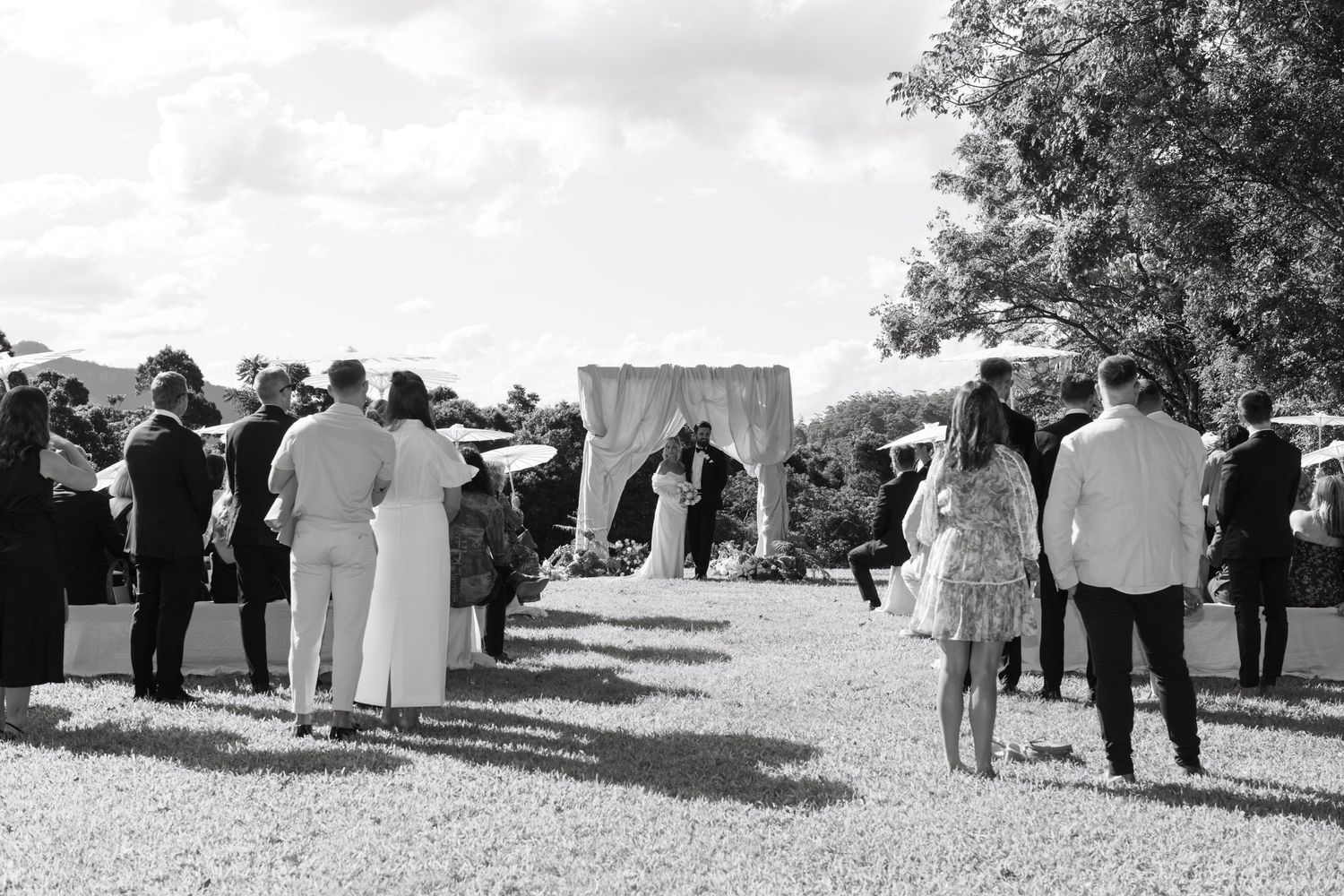 A black and white photo series showing people gathered outdoors for a social event or ceremony.