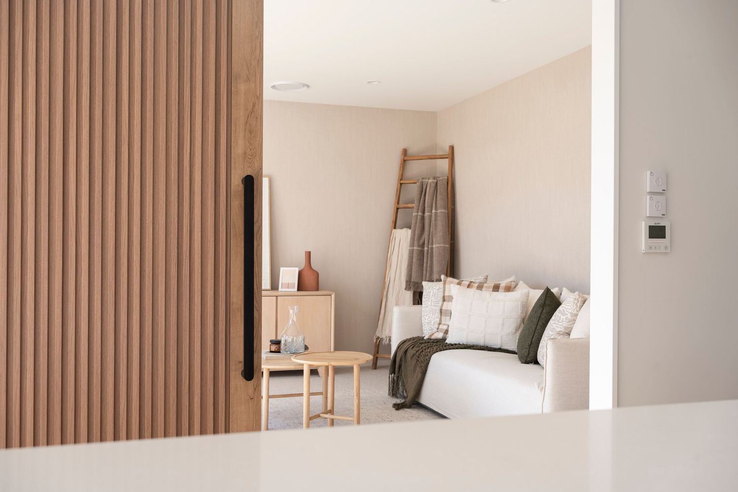 Modern bedroom interior with wooden slat accent wall and neutral color palette.