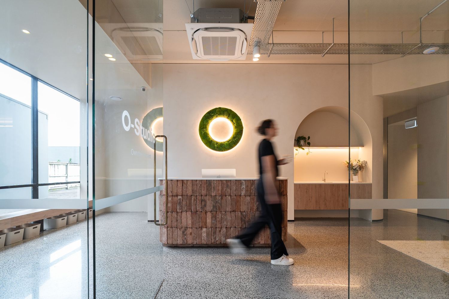 Motion blur of person walking past modern office reception area with circular wall light.