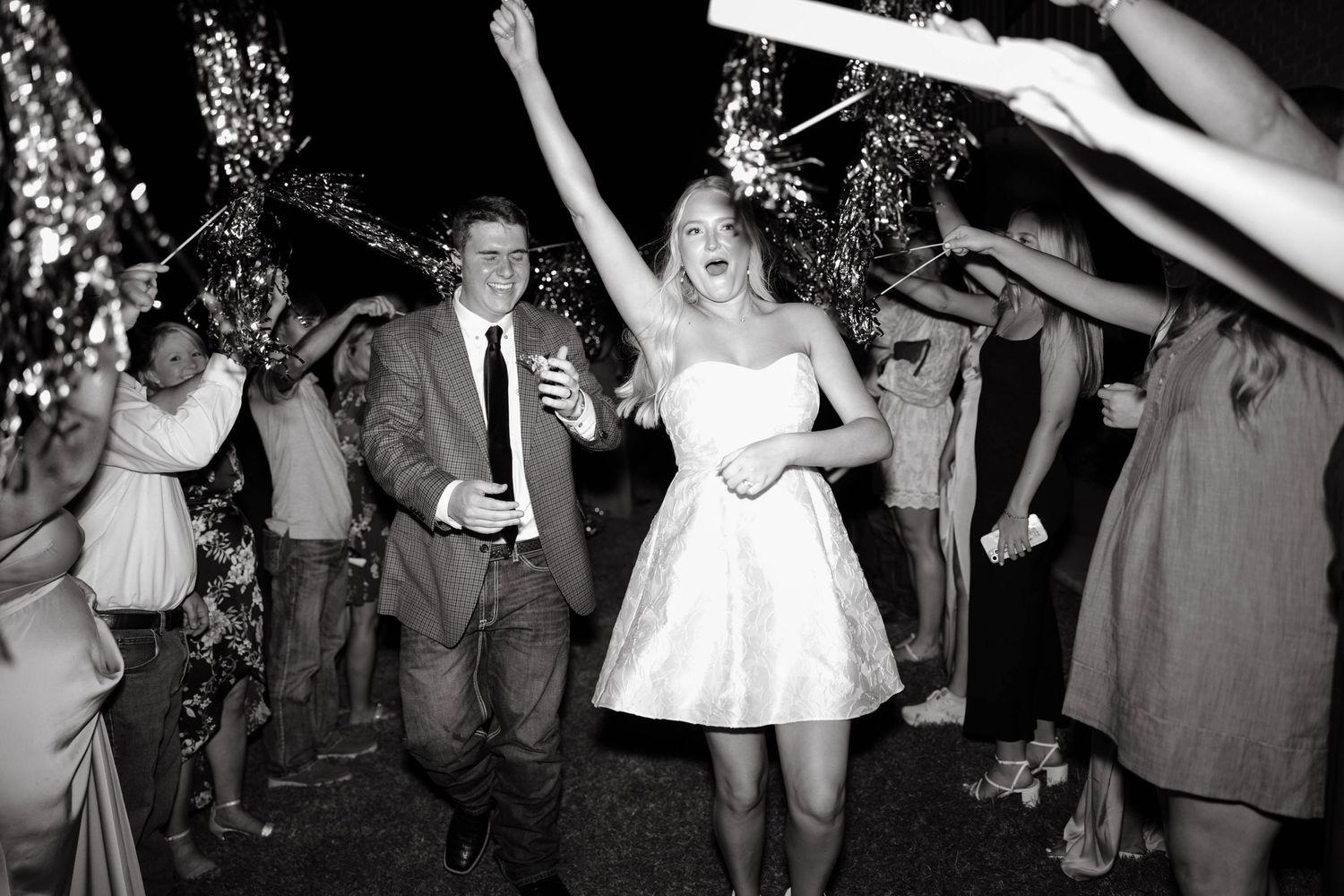 Black and white photo of bride and groom exiting through a sparkler send-off at their wedding.