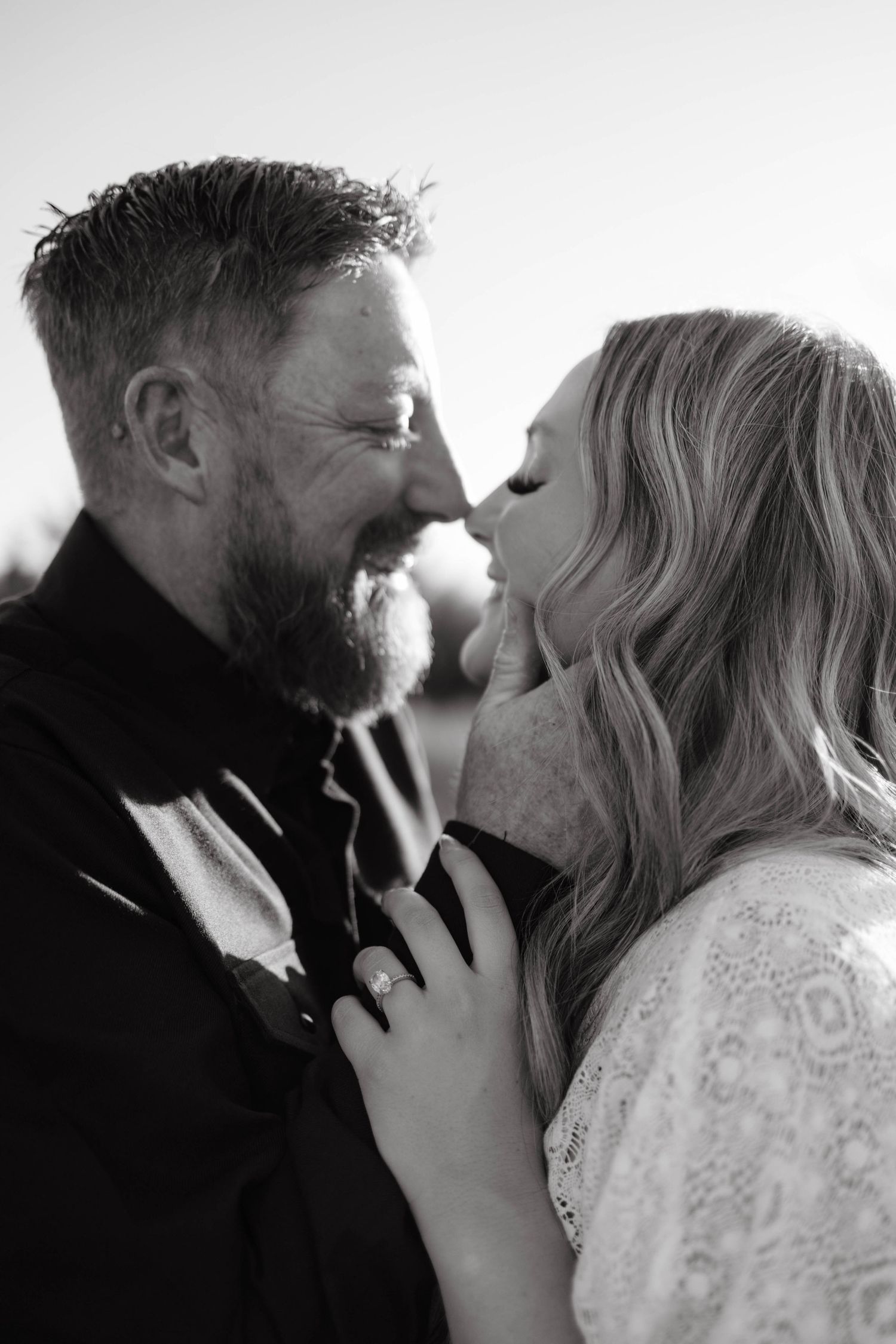 Black and white photo of bearded man and blonde woman sharing a romantic moment.