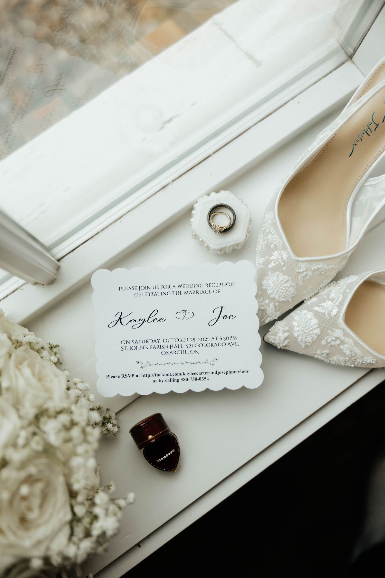 Wedding flat lay with lace heels, invitation for Kaylee and Joe, rings and florals.