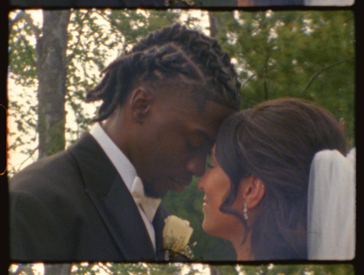 A couple shares an intimate moment at their outdoor wedding ceremony, with the groom in a suit and bride in a veil.