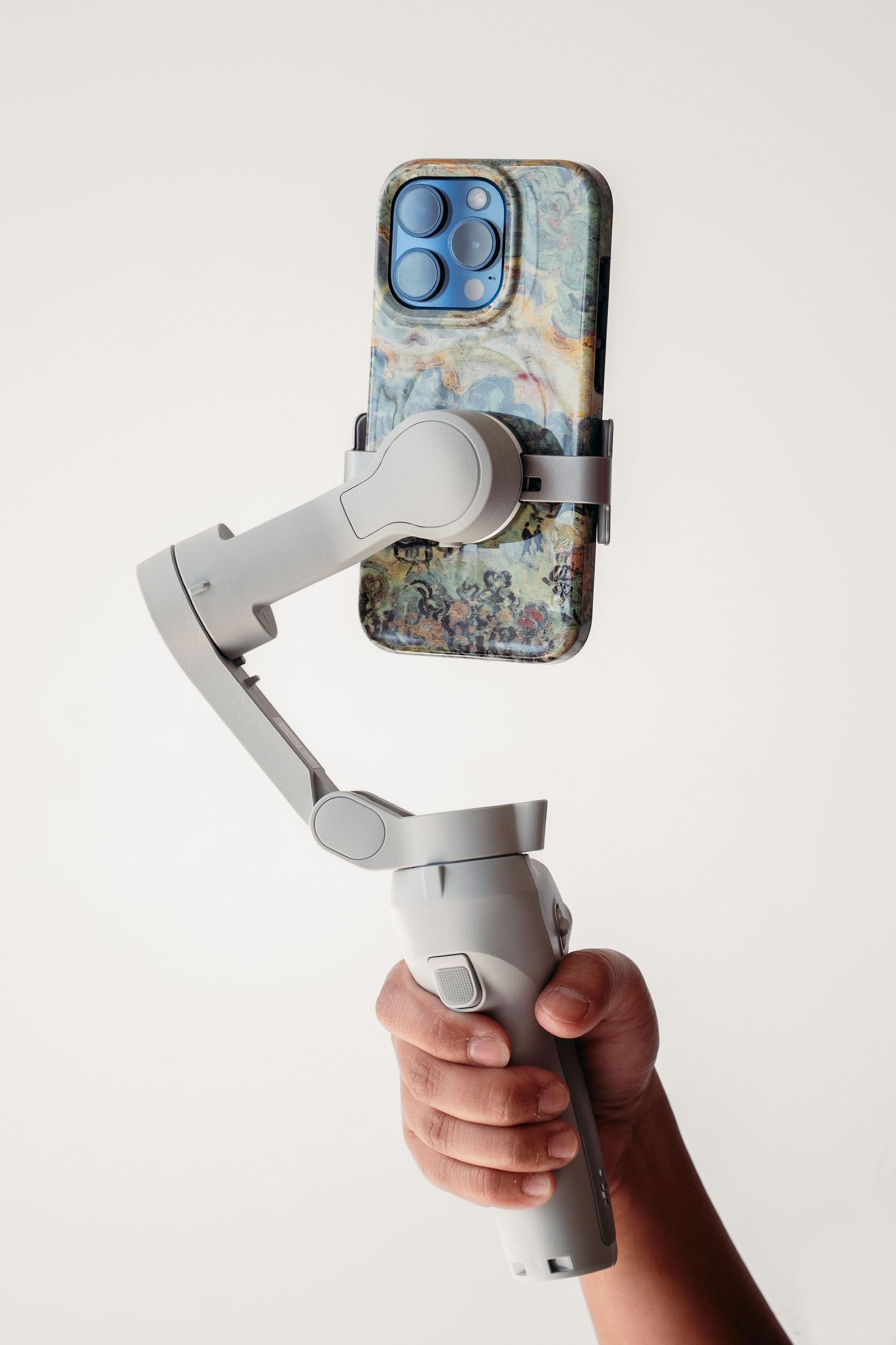 Hand holds a white DJI smartphone gimbal stabilizer shown from multiple angles against a light background.