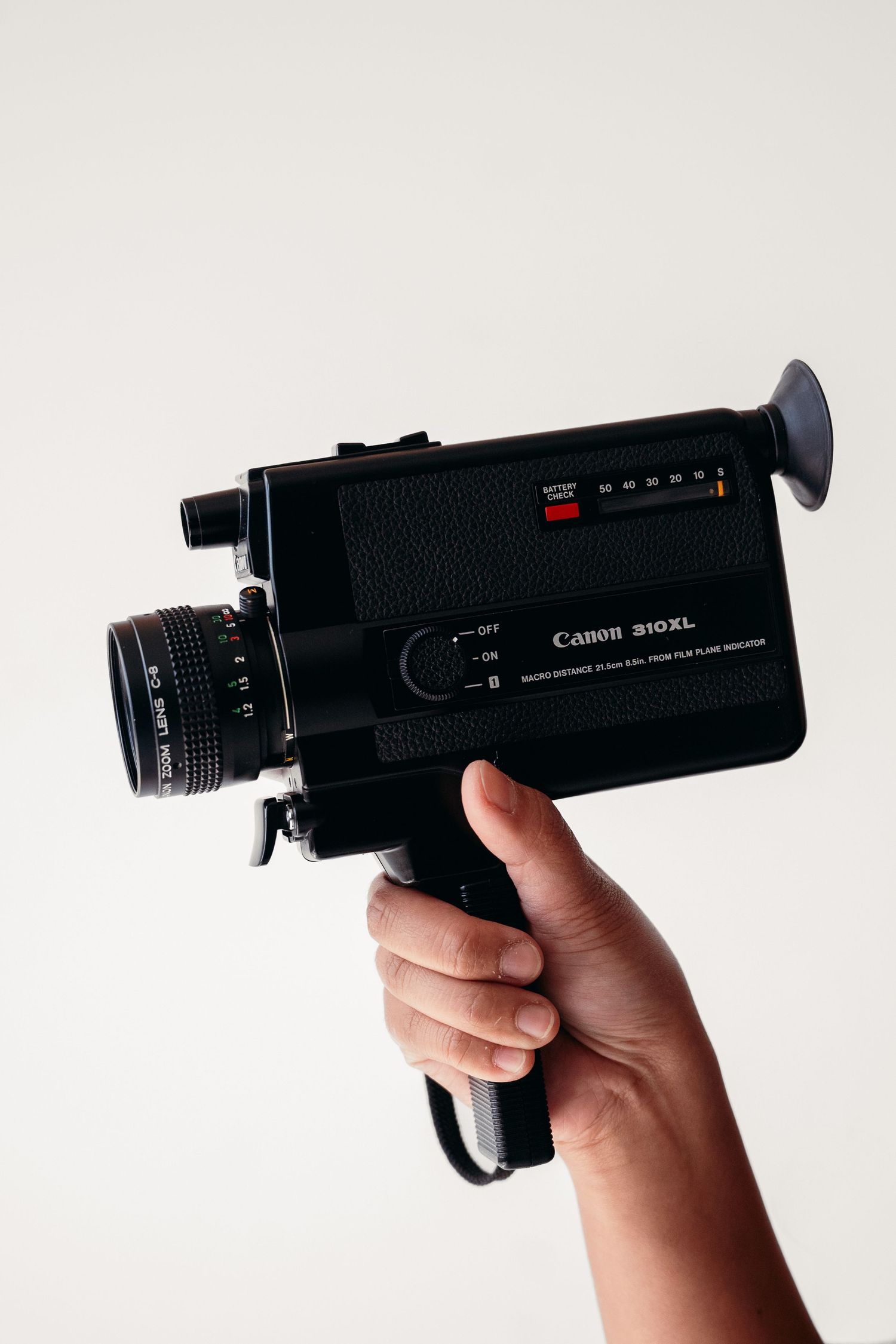 Three views of a vintage Canon 514XL Super 8 movie camera being held against a white background.