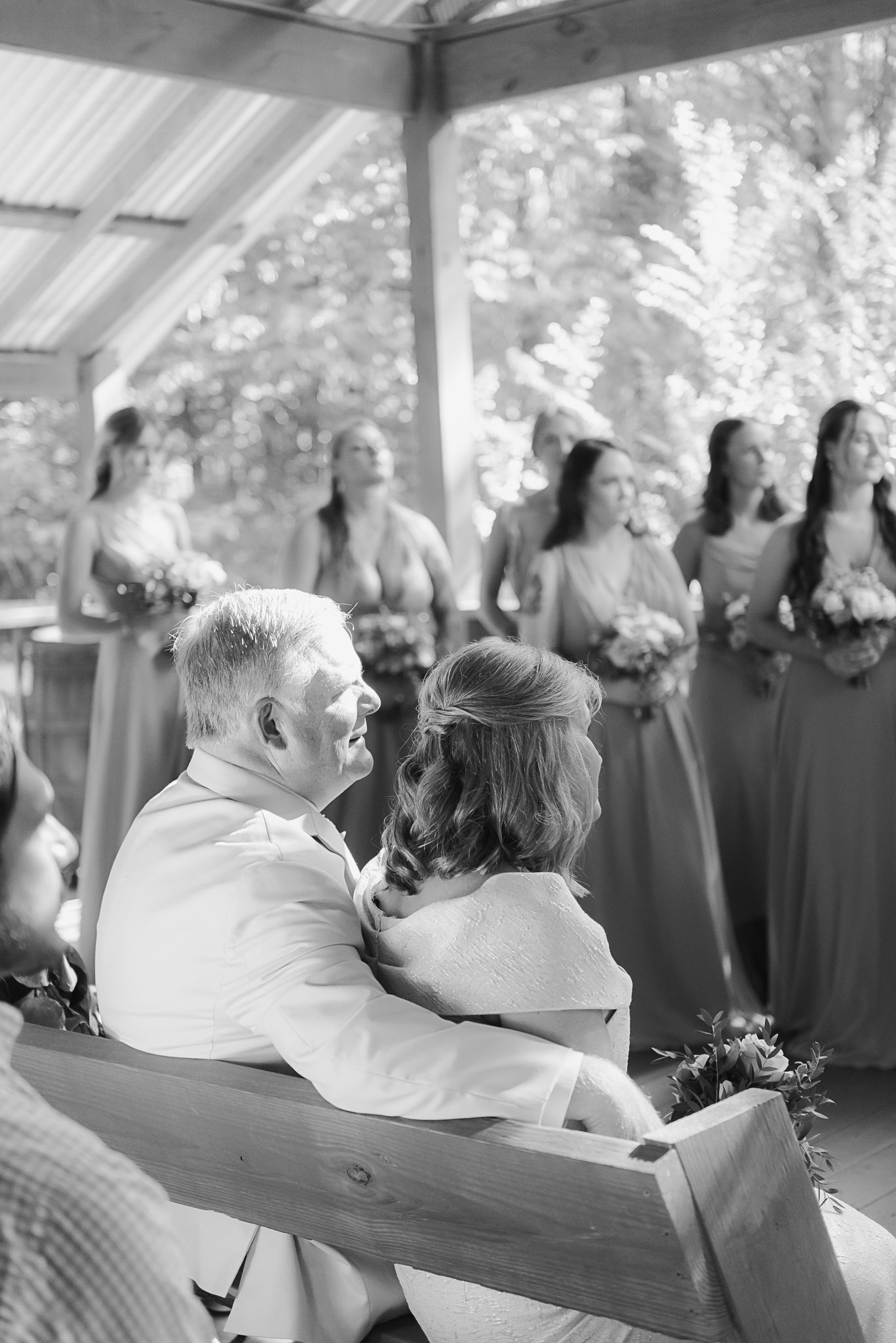 Guests seated on wooden benches at an outdoor covered venue.