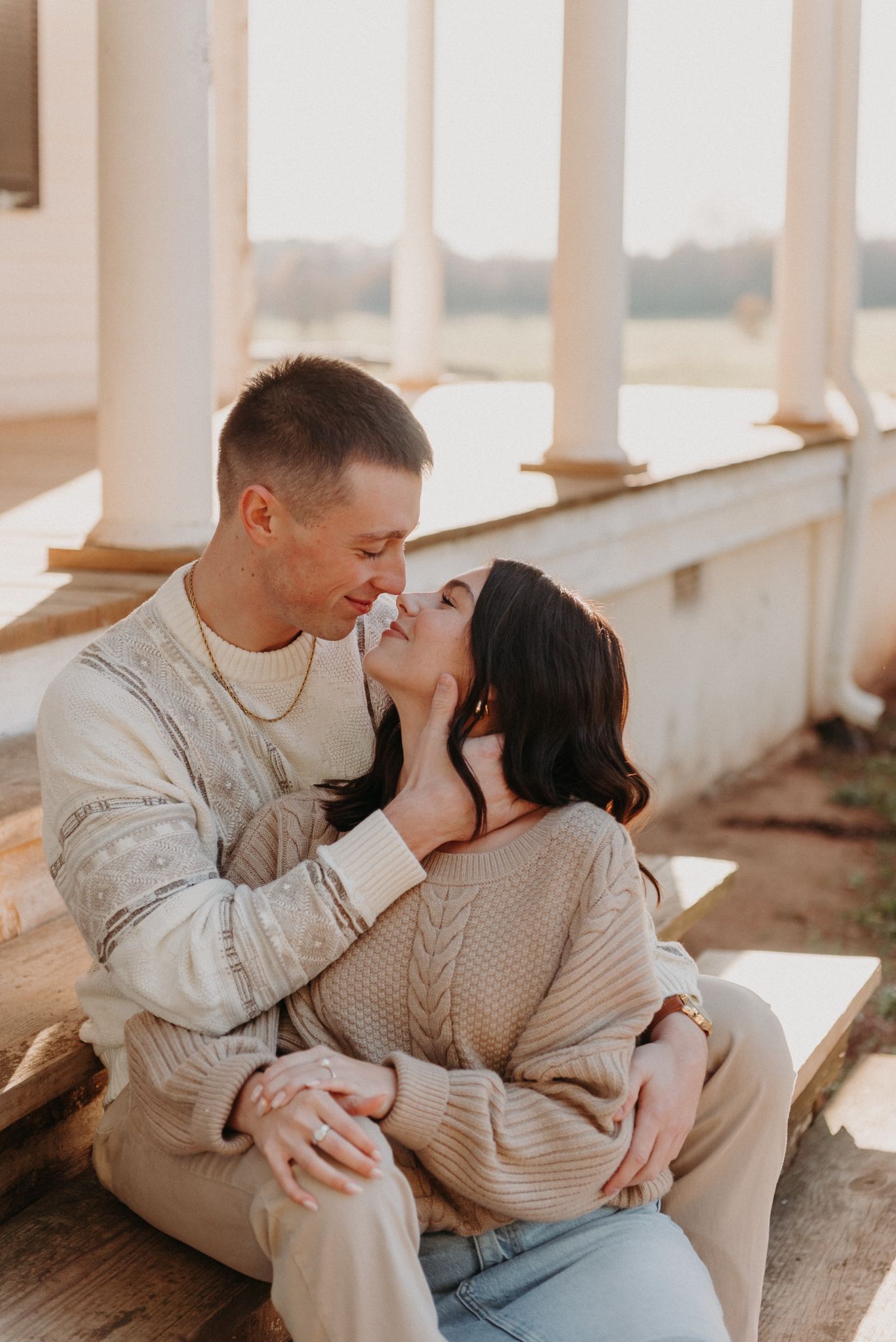 Couple sharing an intimate moment on a porch during golden hour.