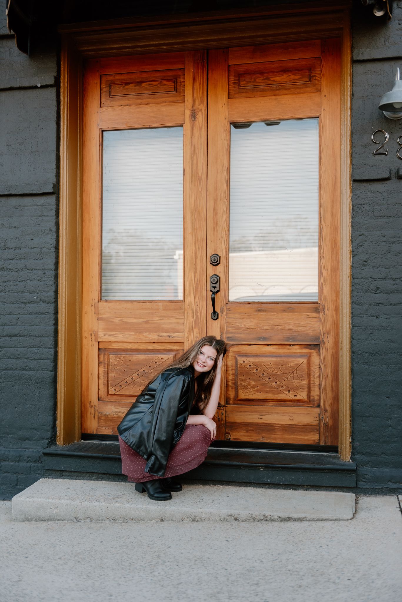 Creative portrait series against wooden doors and grey brick wall.
