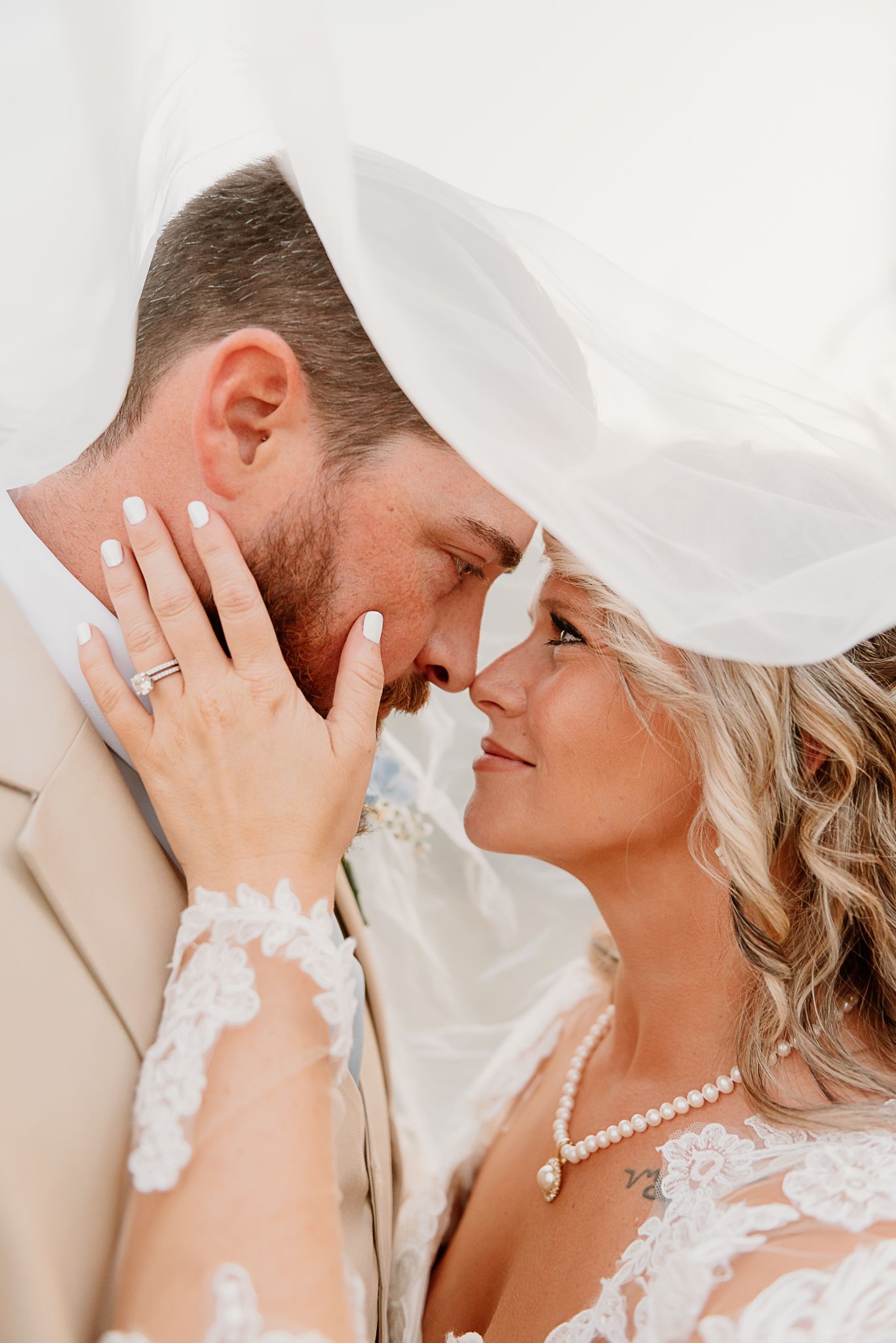 Close-up romantic wedding portrait showing rings and delicate lace details.