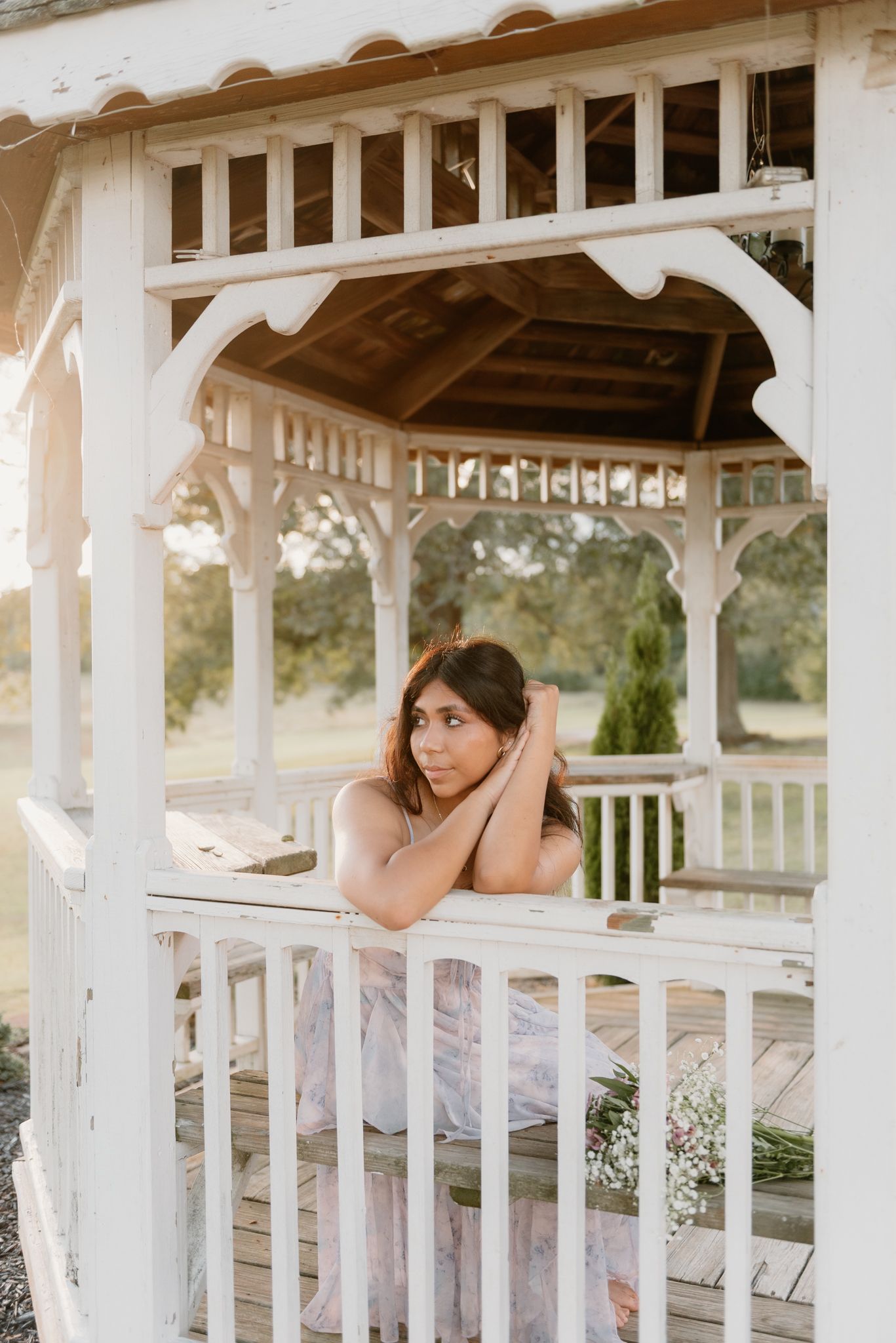 Romantic portrait session in a white wooden gazebo during golden hour.