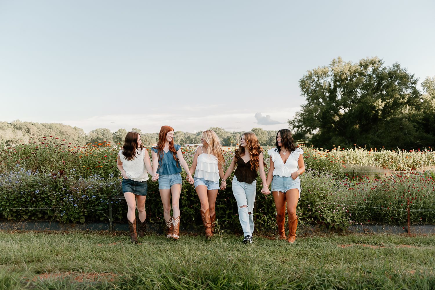 Group of friends walking together through a sunny meadow at sunset.