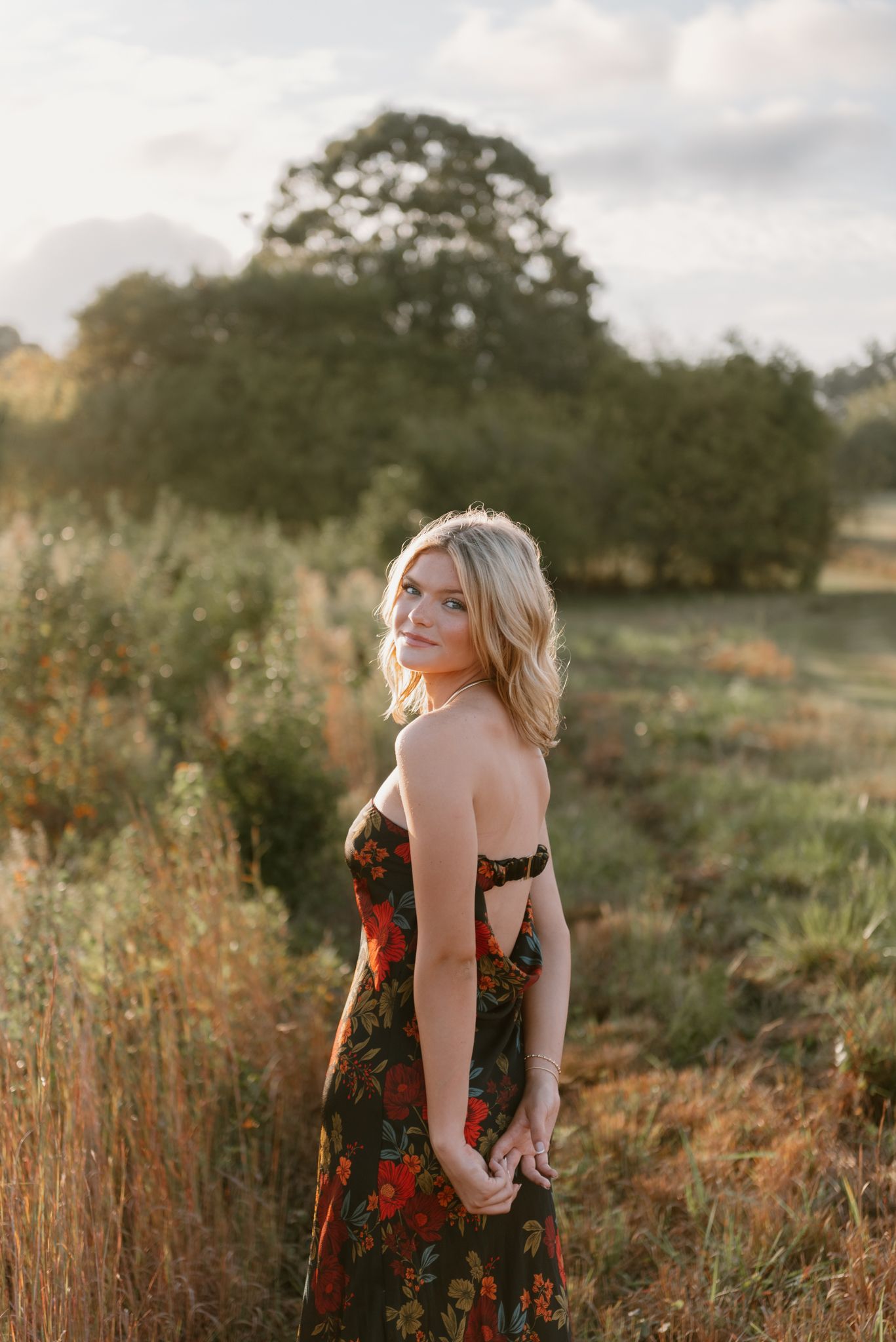 Natural outdoor portrait session in a rustic field with tall grass at golden hour.