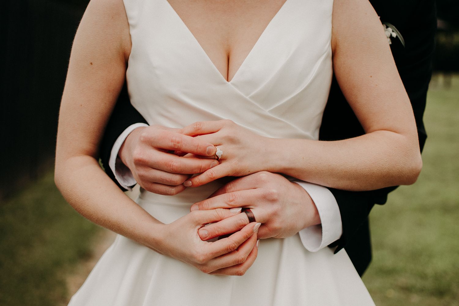 Close up details of white wedding dress bodice and hands.
