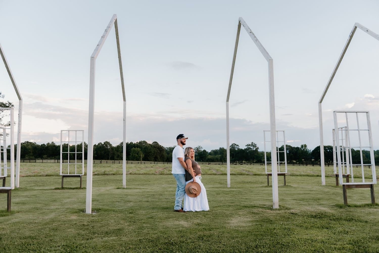 White vertical poles stand in neat rows across a grassy field under an overcast sky.