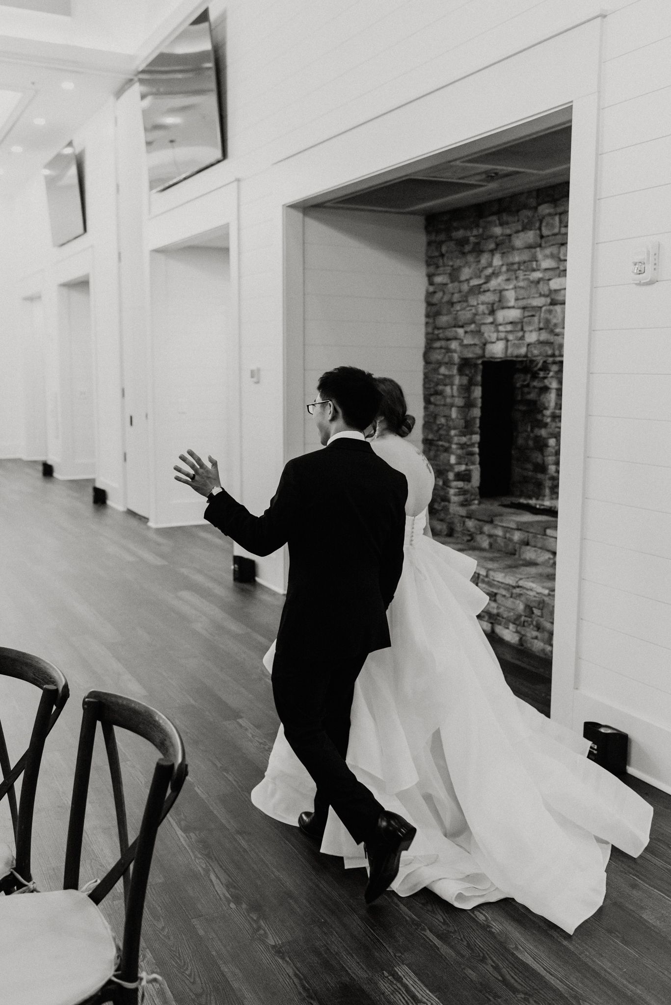 Black and white photo of couple dancing in an elegant indoor venue with hardwood floors.