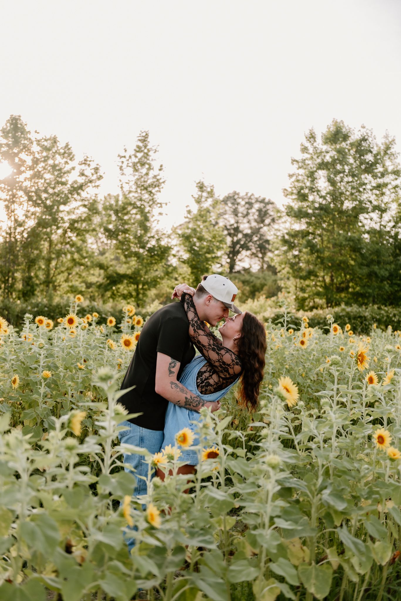 A romantic moment captured in a sunflower field during golden hour.