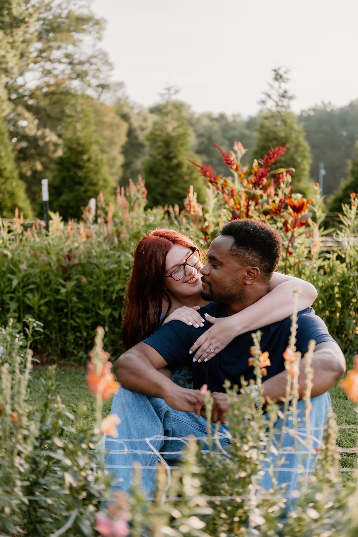 Couple embracing in wildflower garden during golden hour.