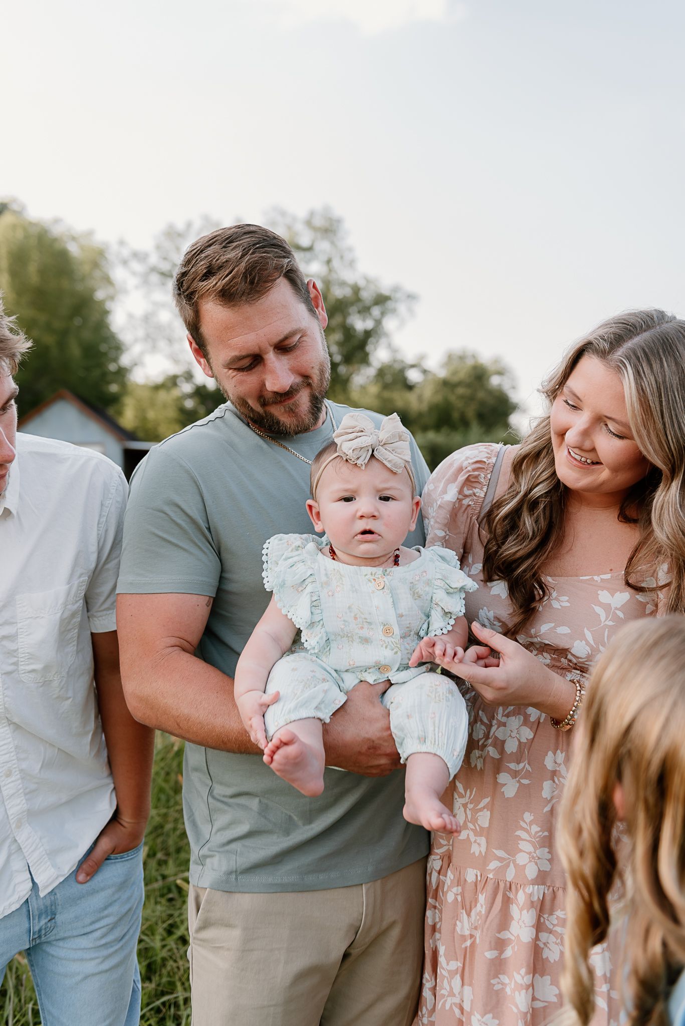 Outdoor family gathering with a baby wearing a light blue outfit on a sunny day.