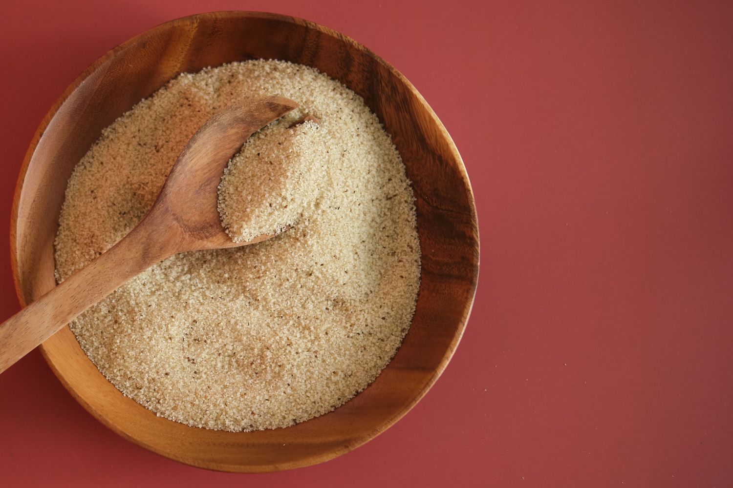 Bowl of fonio on a red background.