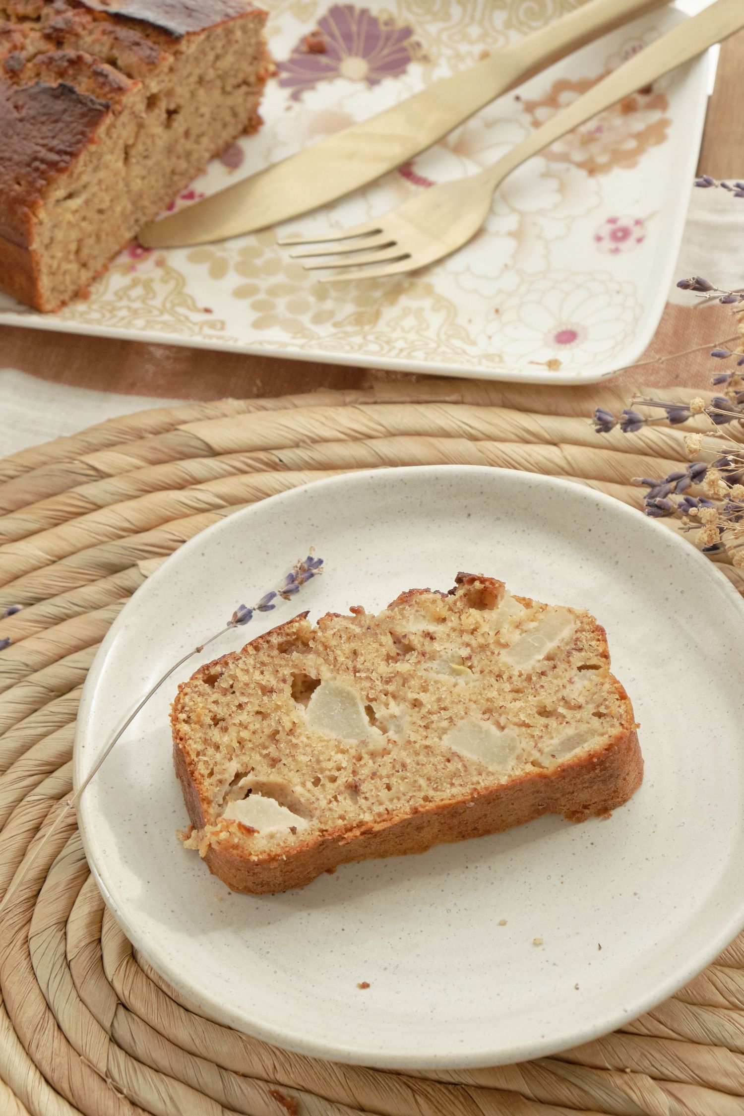 Fresh-baked pear and brown butter cake slices served on white plates with rustic rope mat underneath.