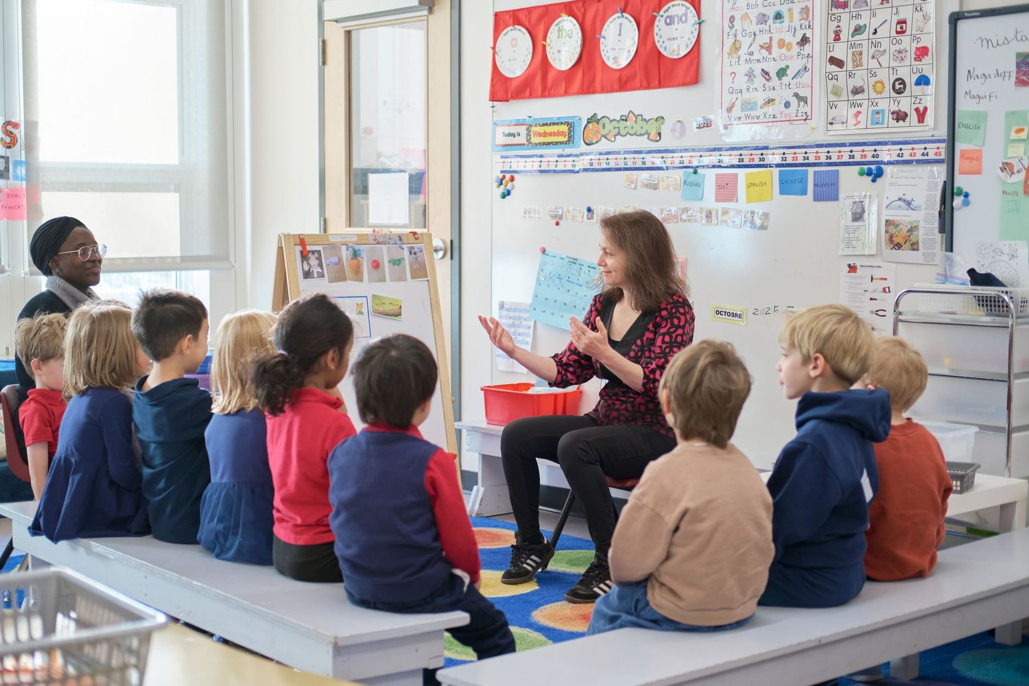Students sitting at desks in a bright classroom with educational posters on the walls.