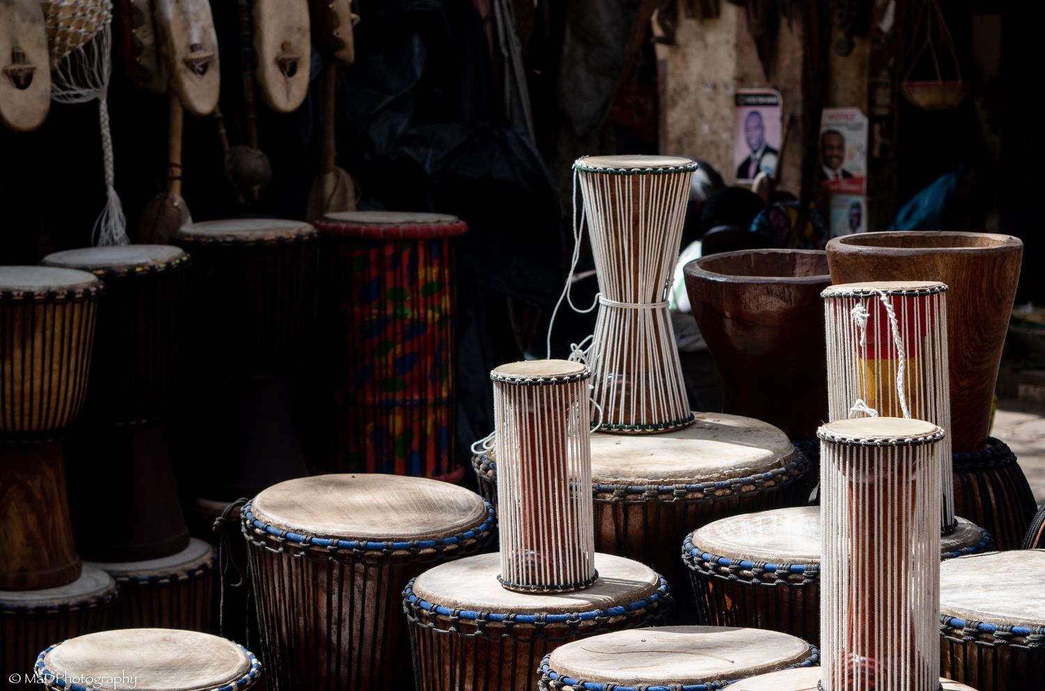 Row of traditional African drums arranged in a dark setting with dramatic lighting.