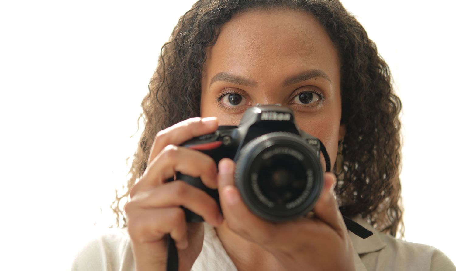 Photographer with curly hair taking pictures using black digital camera.