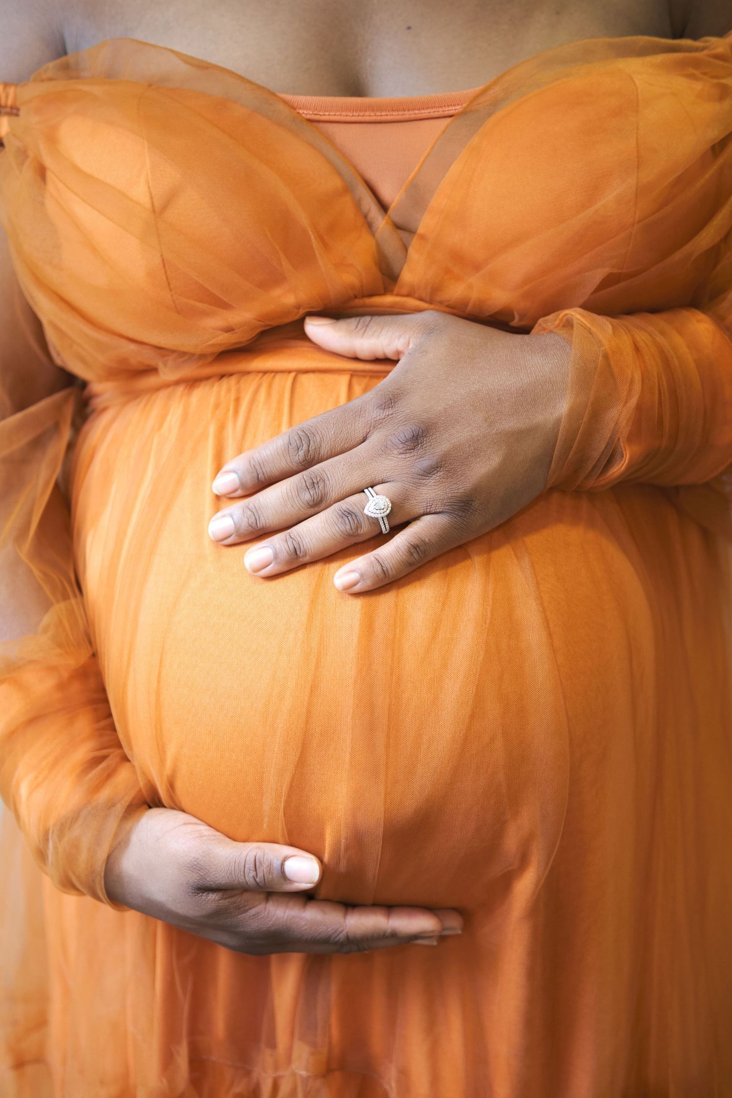 A series of photos showing hands cradling a pregnant belly draped in flowing orange fabric against a warm background.
