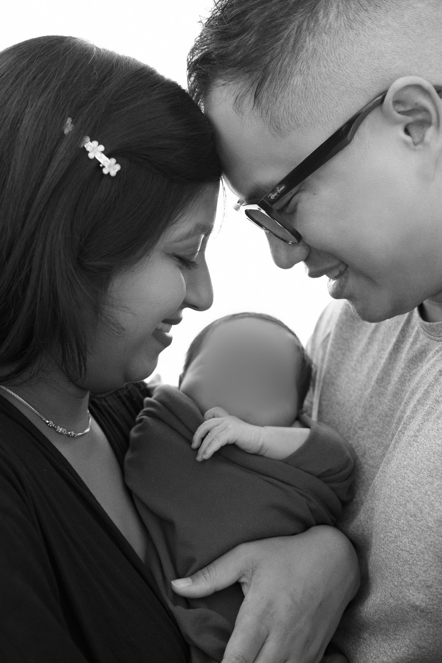 Black and white photo series showing tender moments between parents and their newborn baby in intimate close-up shots.