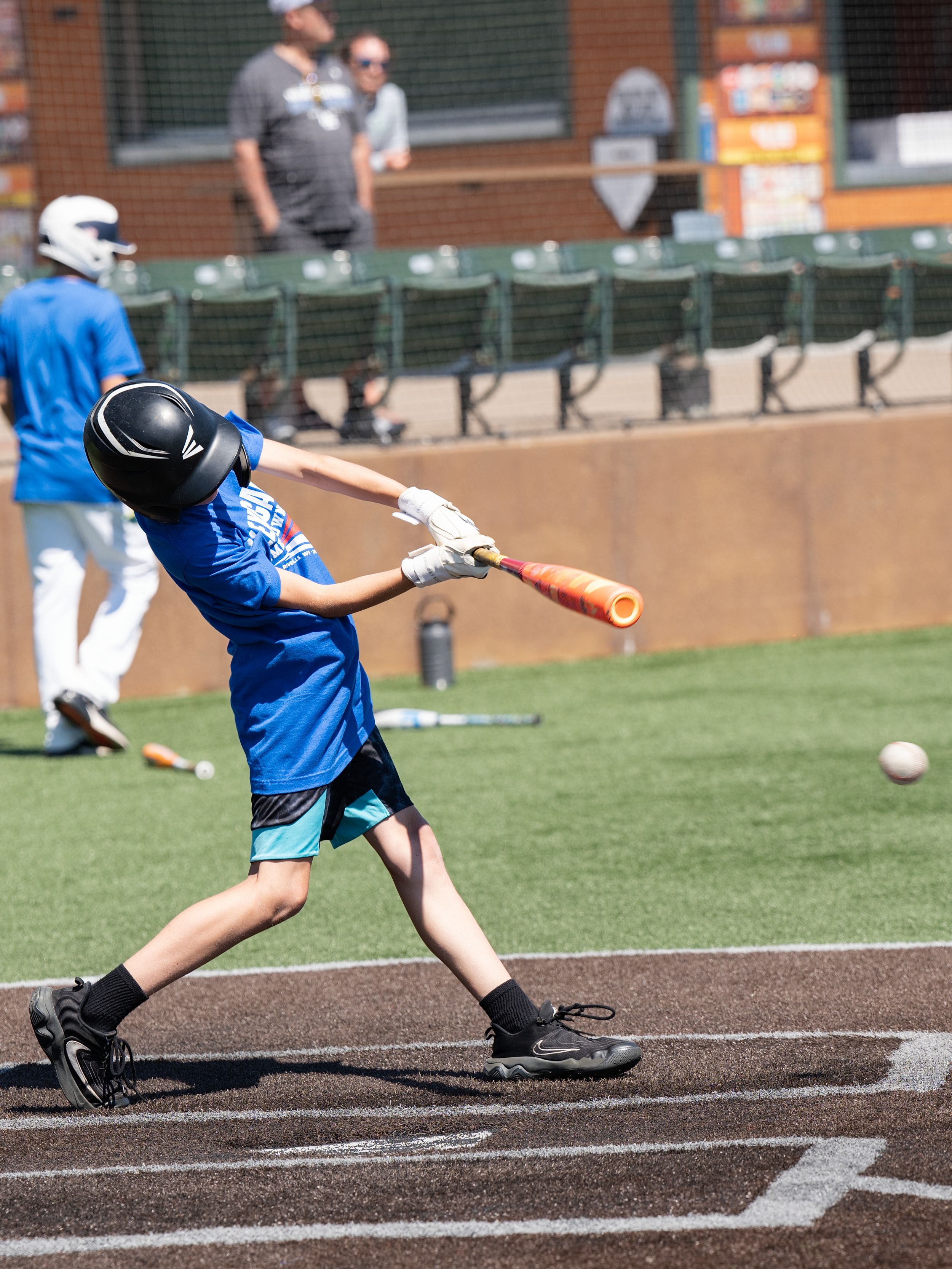 A young batter in a blue jersey swinging at a ball on a ballpark field