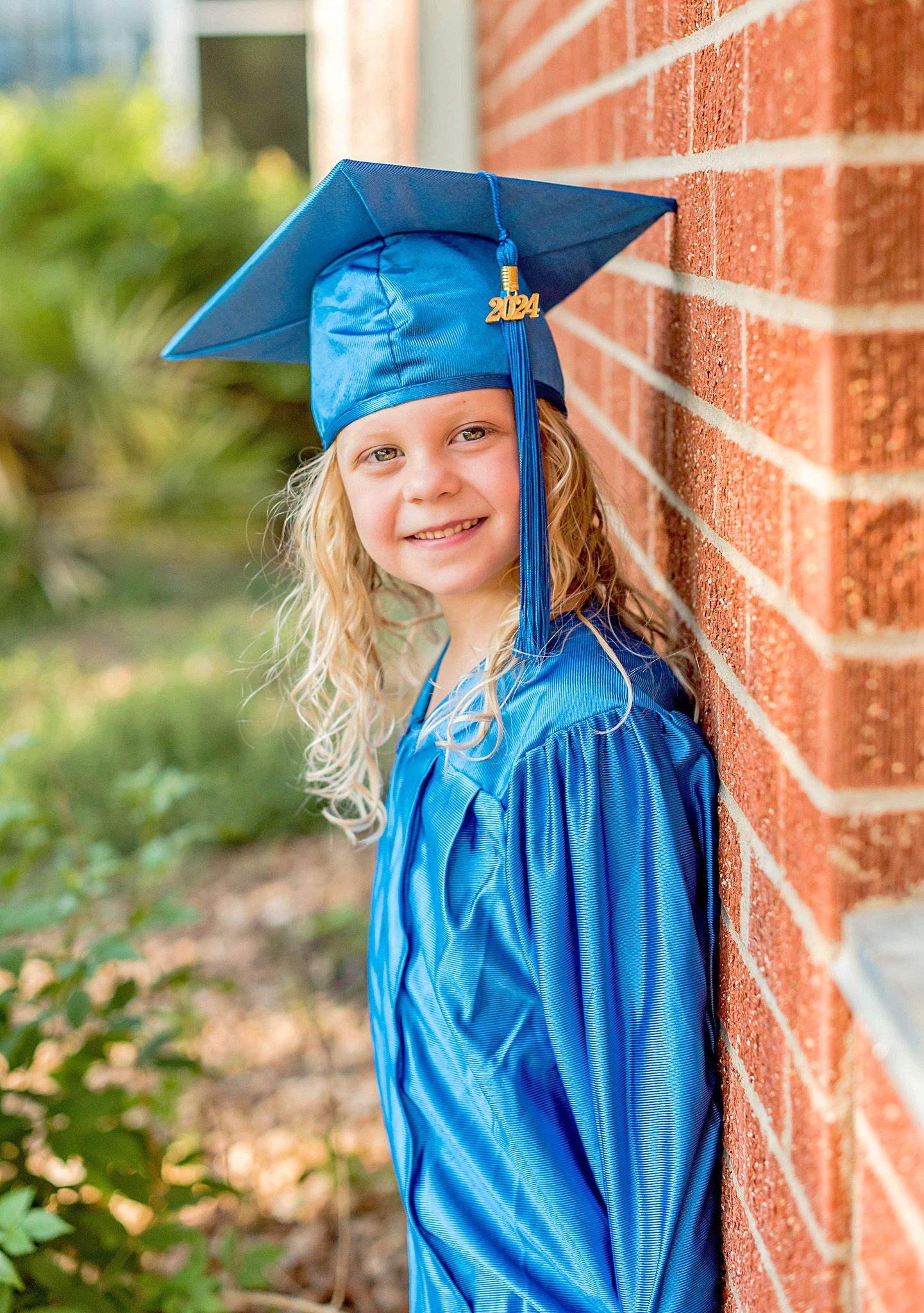 A series of graduation photos showing a young graduate in bright blue cap and gown posing against a brick wall.