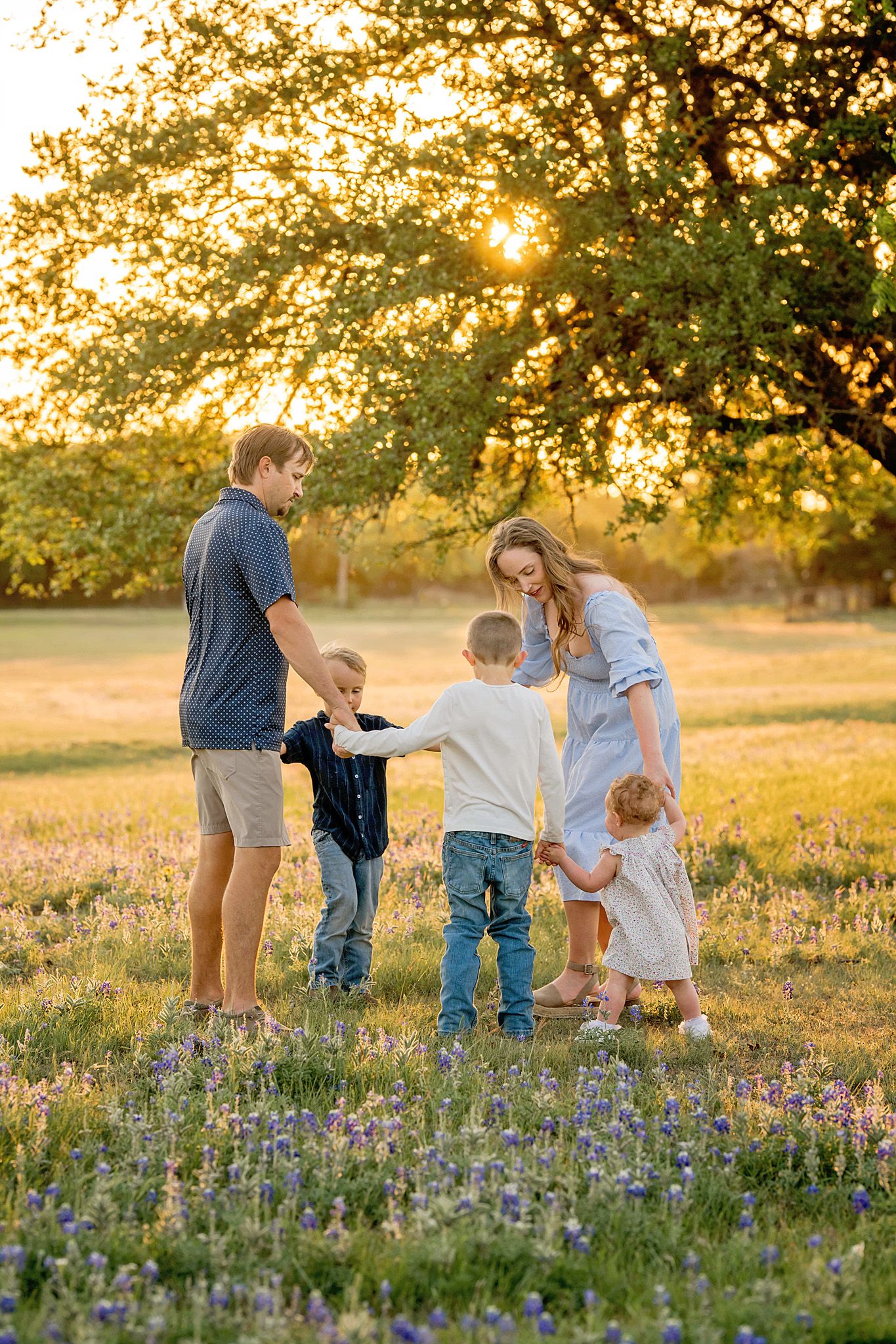 Family walking through blooming wildflowers at golden hour.