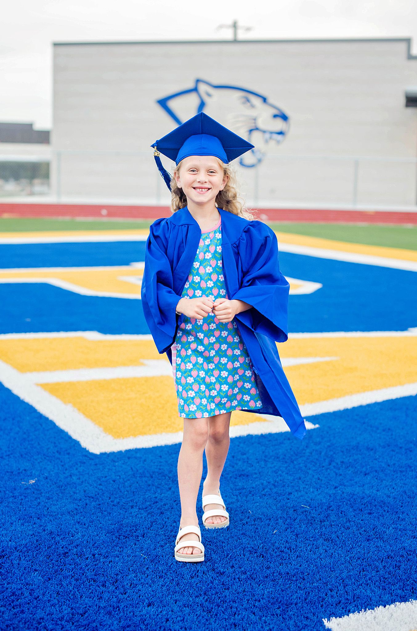A series of photos showing a graduate in a blue cap and gown walking across a bright blue and yellow patterned field.