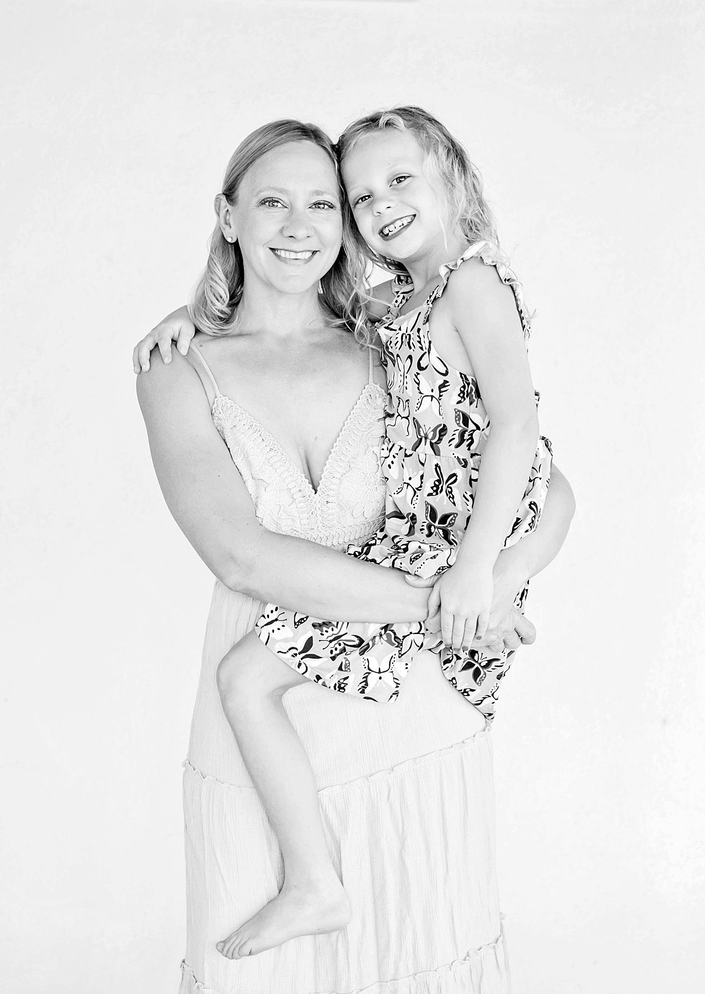 Three black and white portraits of a parent and child embracing in matching floral outfits against a white background.