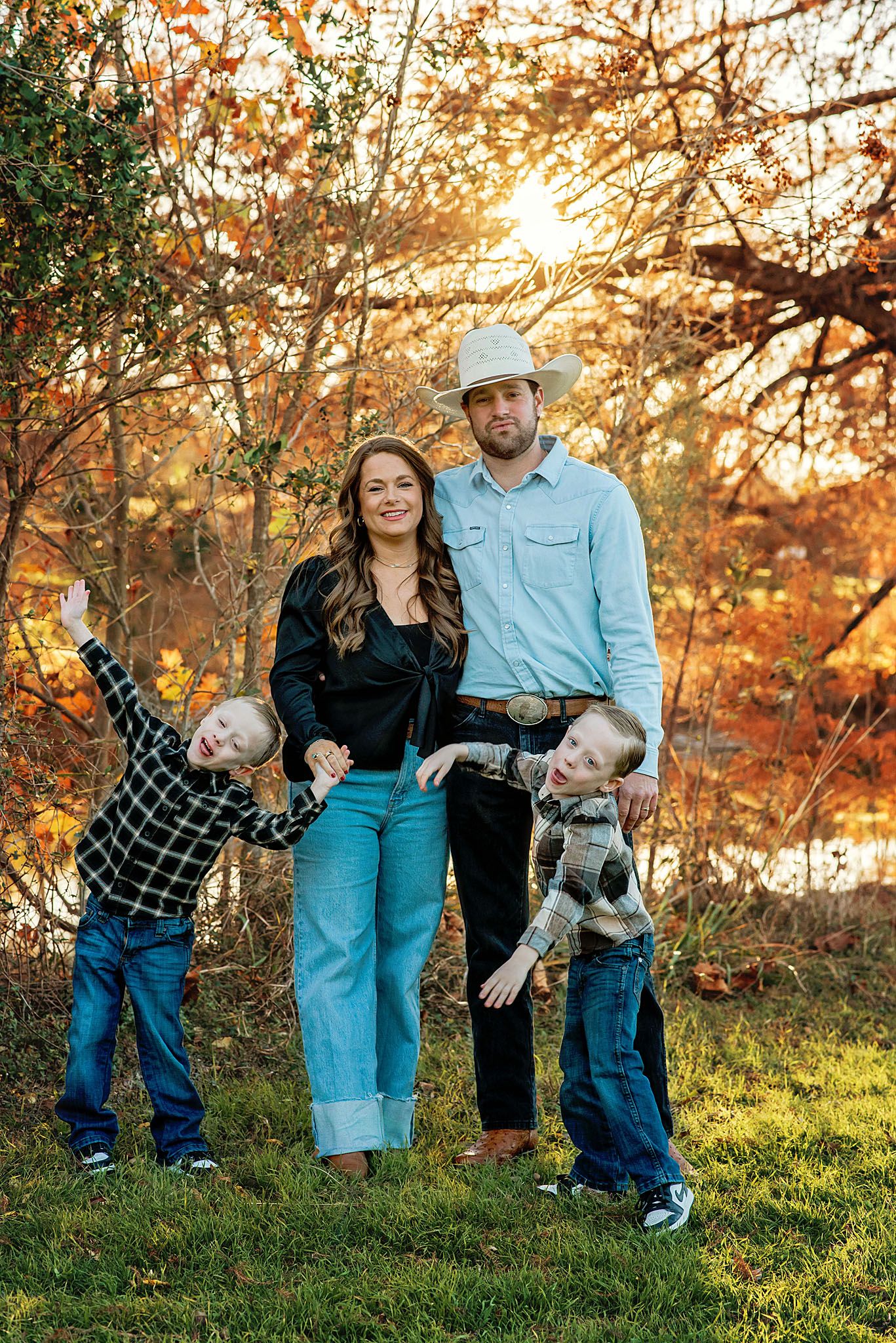 Family enjoying autumn sunset together in park with golden fall foliage and warm lighting.