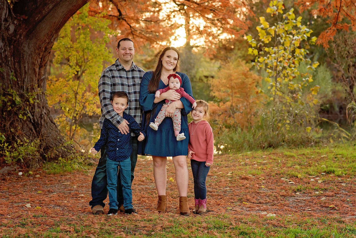 Autumn outdoor photo session in a park with golden sunlight filtering through colorful fall foliage.
