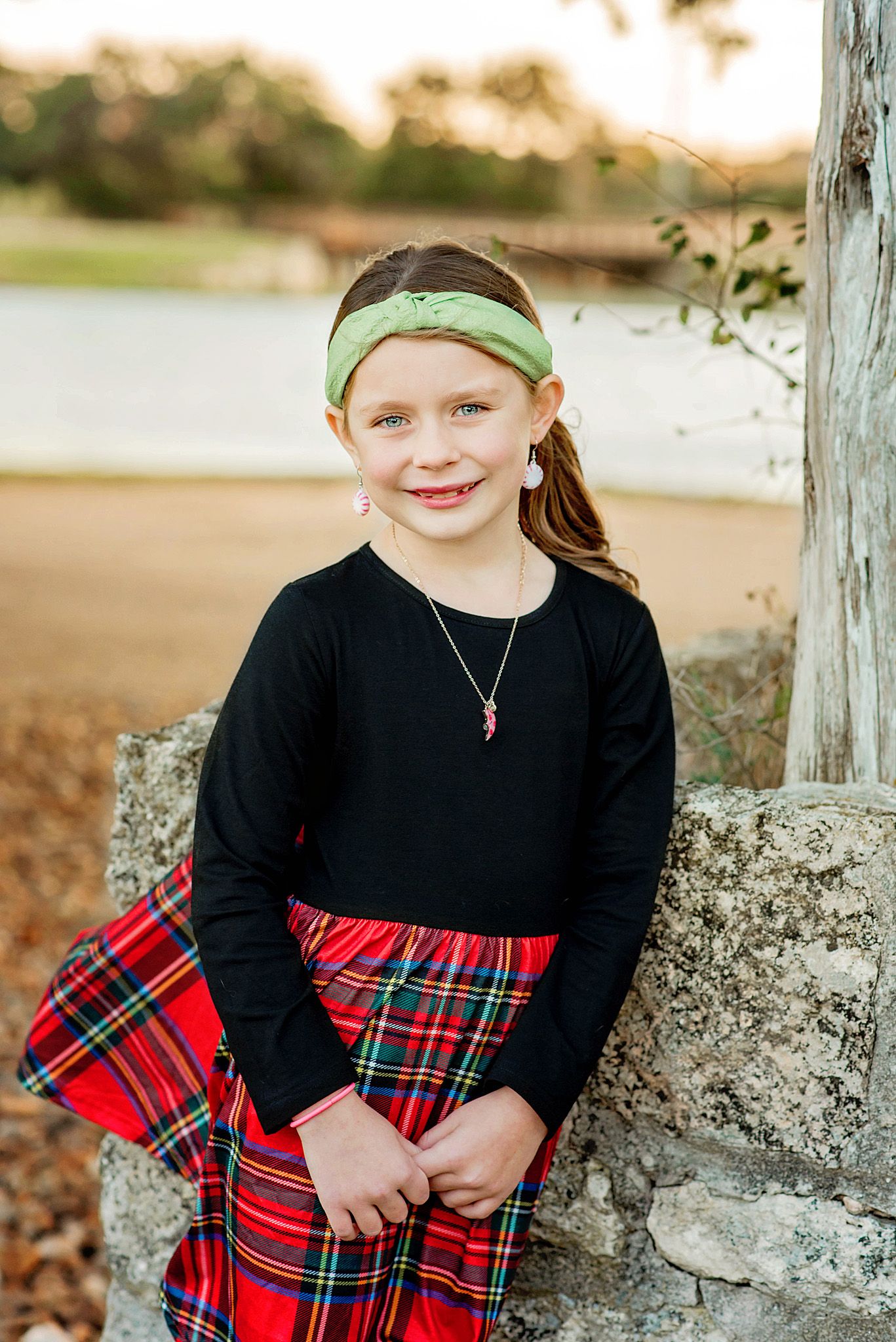A series of three similar photos showing someone wearing a black top with a red plaid skirt against a stone wall outdoors.