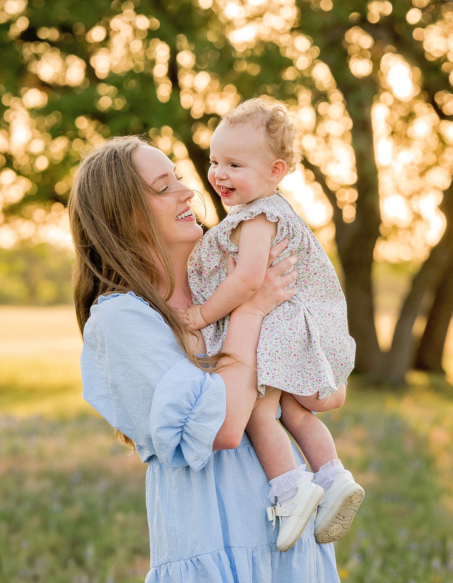 A parent and child share joyful moments together in a sun-dappled outdoor setting at golden hour.