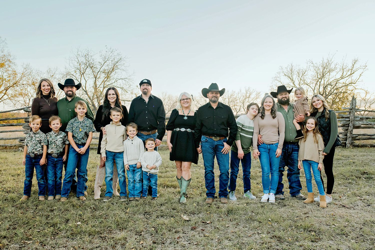 Extended family in matching western outfits posing on a ranch in autumn.