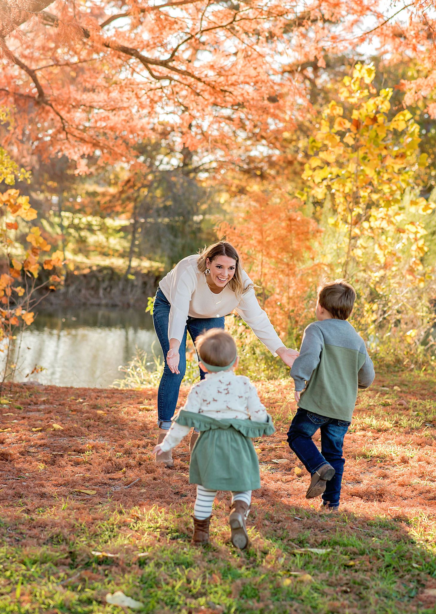 A family plays together in a park filled with vibrant autumn foliage on a sunny fall afternoon.