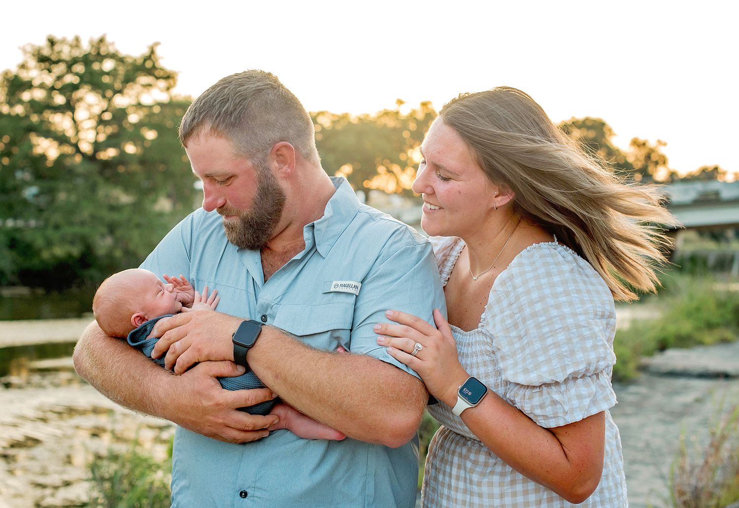 A family wearing blue and white outfits poses together during a sunset photo session at the beach.