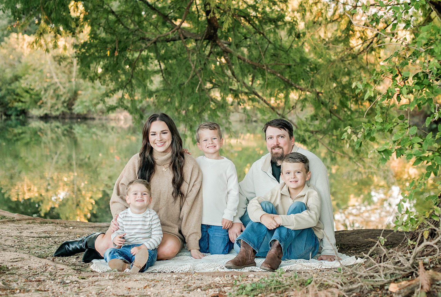 Family enjoying a warm autumn day together outdoors in a natural setting with golden sunlight filtering through trees.