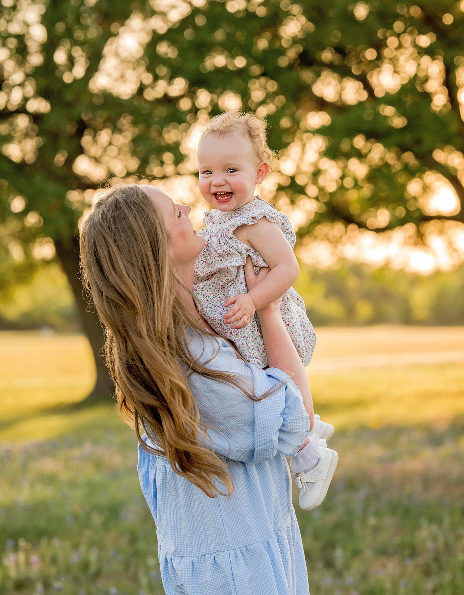 Mother and baby sharing playful moments in a sunny outdoor setting.