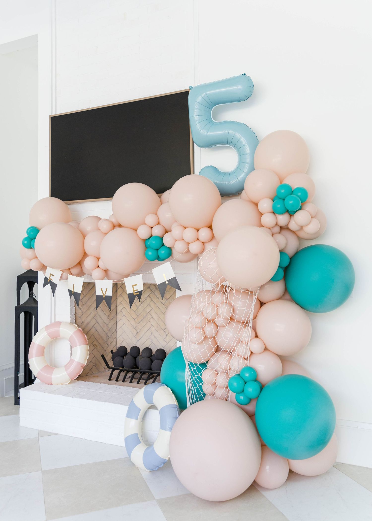 Modern balloon arch installation with pink and turquoise balloons against white wall.