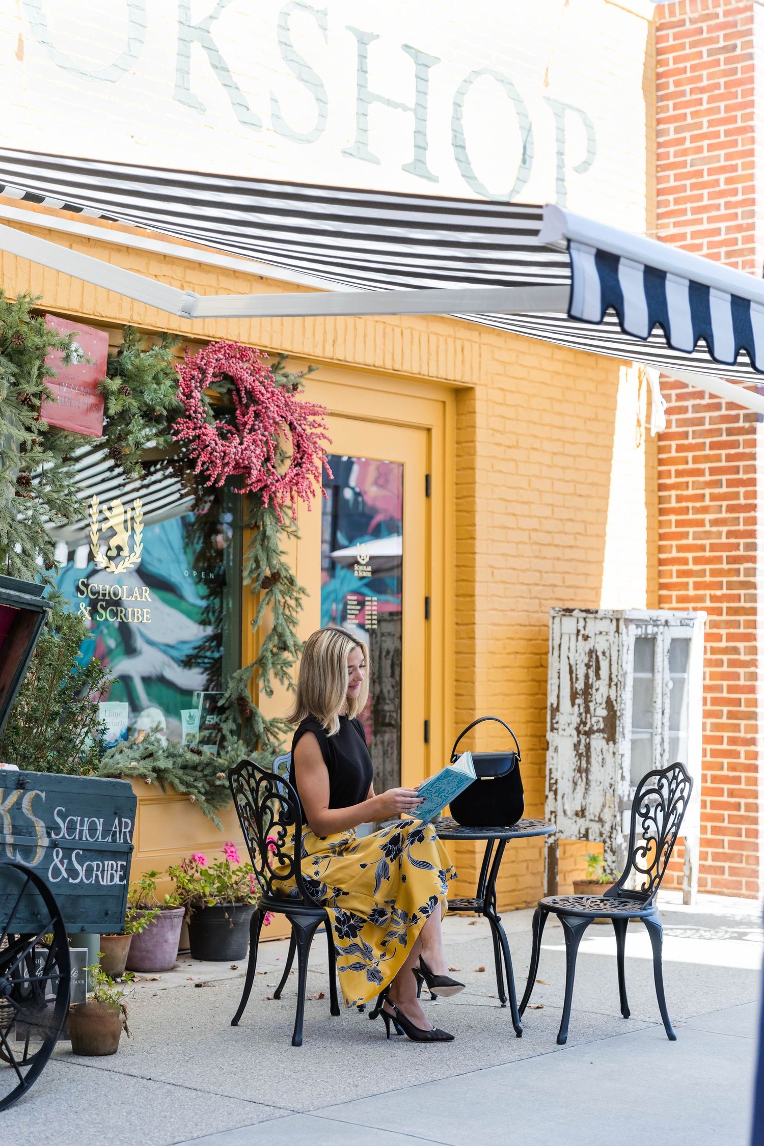 A storefront with wrought iron chairs and pink flowers creating an inviting outdoor seating area.