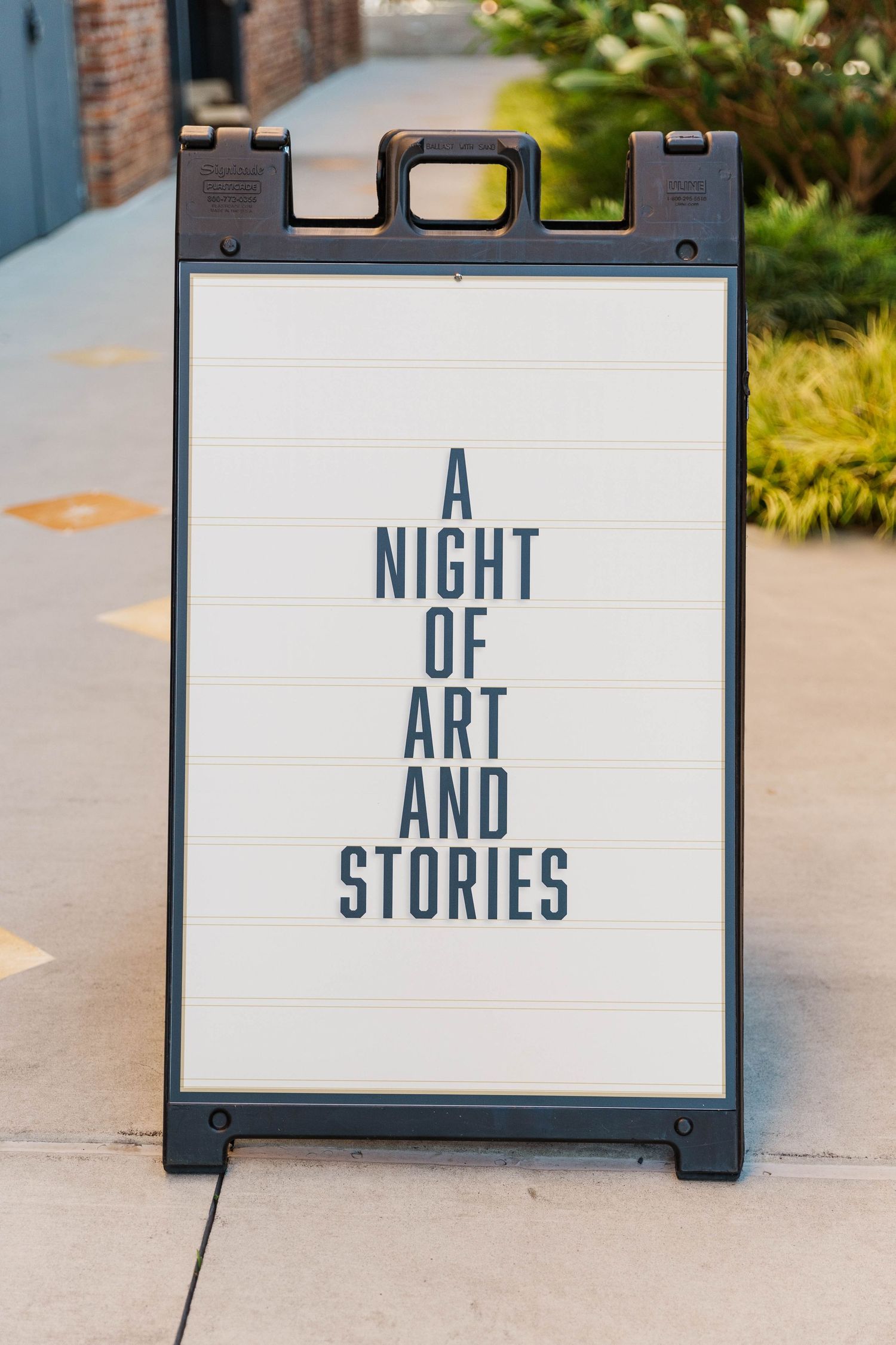 Outdoor signage reading 'A Night of Art and Stories' displayed on white panels.
