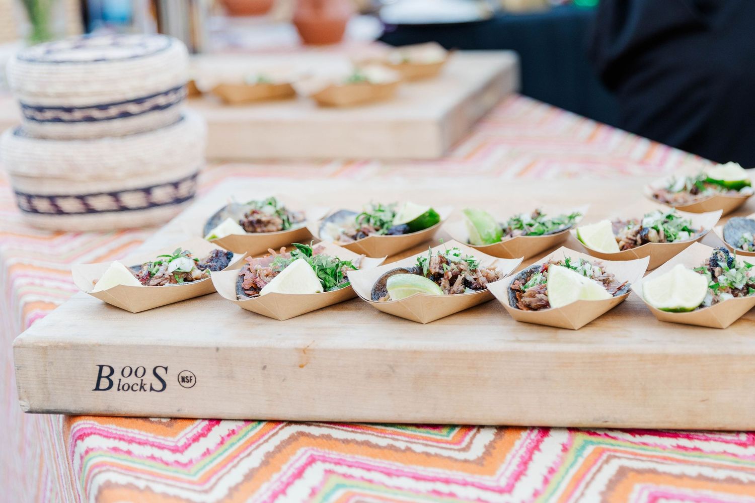 Row of appetizers plated on small dishes displayed on a pink patterned tablecloth.